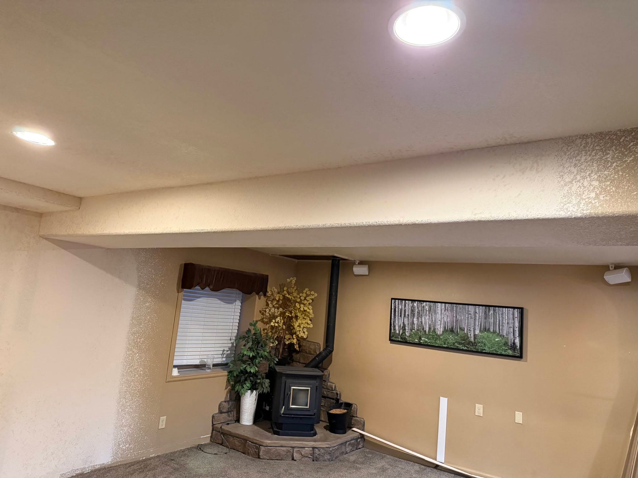 Finished living room with stone fireplace and recessed lighting